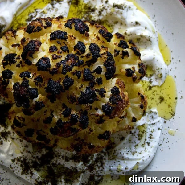 A an overhead shot of a plate of whole roasted cauliflower with lemony yogurt sauce.