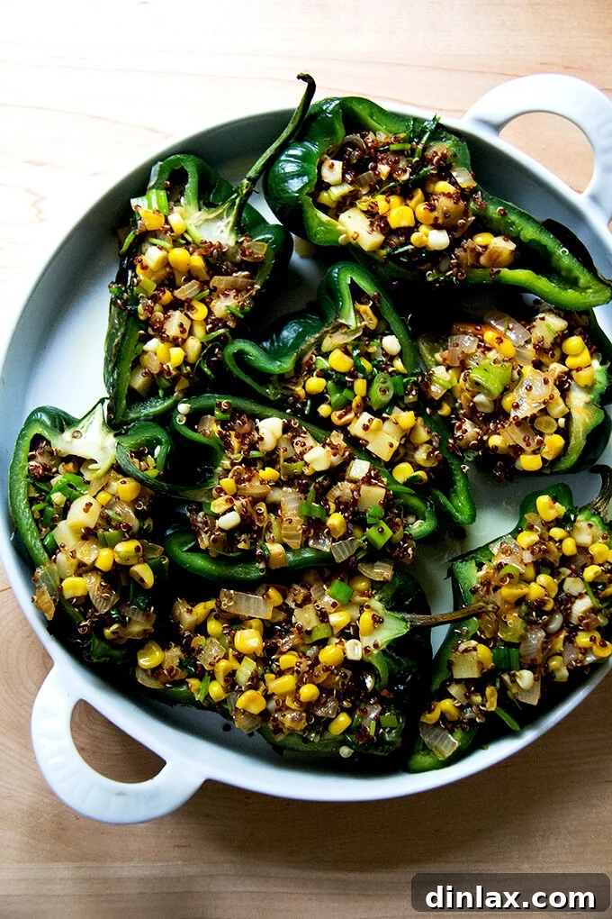 A baking dish filled with halved poblano peppers generously stuffed with the corn and quinoa mixture, topped with cheese, ready for the oven.