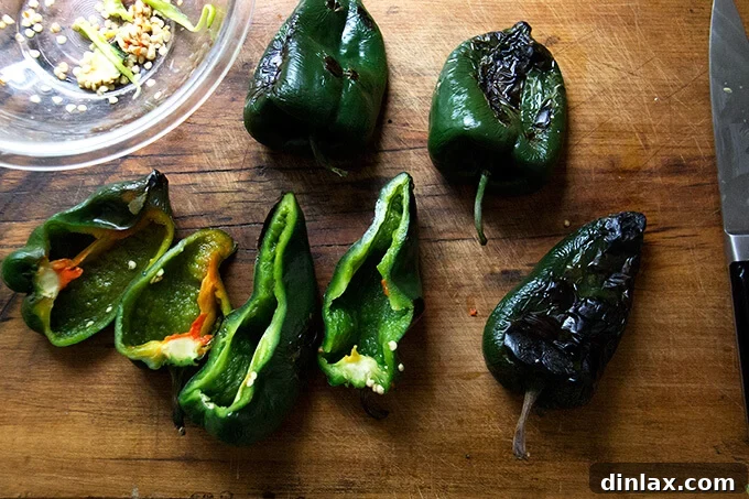 Blistered poblano peppers, carefully halved and deseeded, lie ready to be filled with the savory corn and quinoa mixture.