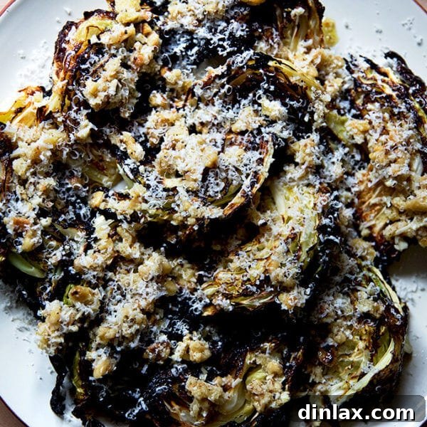 A plate of golden-brown roasted cabbage wedges beautifully topped with a vibrant walnut, Parmesan, and balsamic salsa, showcasing a delicious blend of textures and colors.