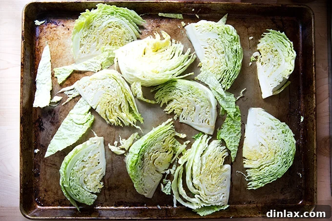 A sheet pan filled with perfectly spaced Savoy cabbage wedges, lightly coated in oil and seasoning, ready to be roasted.