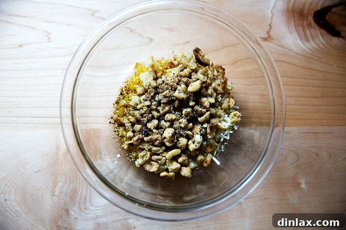 A mixing bowl filled with the fresh ingredients for the walnut salsa: garlic, olive oil, parmesan, bread crumbs, walnuts, lemon juice, and seasonings.