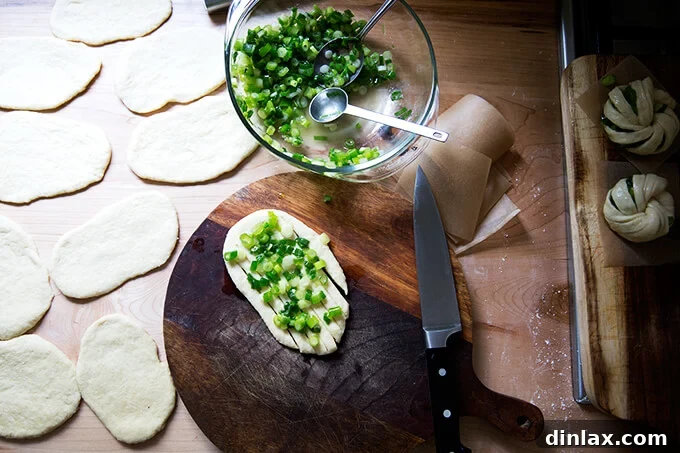 Chinese Steamed Scallion Twists 11 A board with a rolled-out oval of dough, topped with the scallion mixture and slits.