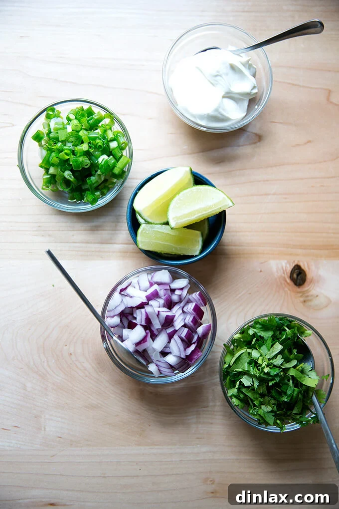 Hearty Black Bean Soup 12 A beautifully arranged countertop with all the essential garnishes for black bean soup: creamy sour cream, vibrant scallions, fresh lime wedges, crisp red onion, and aromatic cilantro.