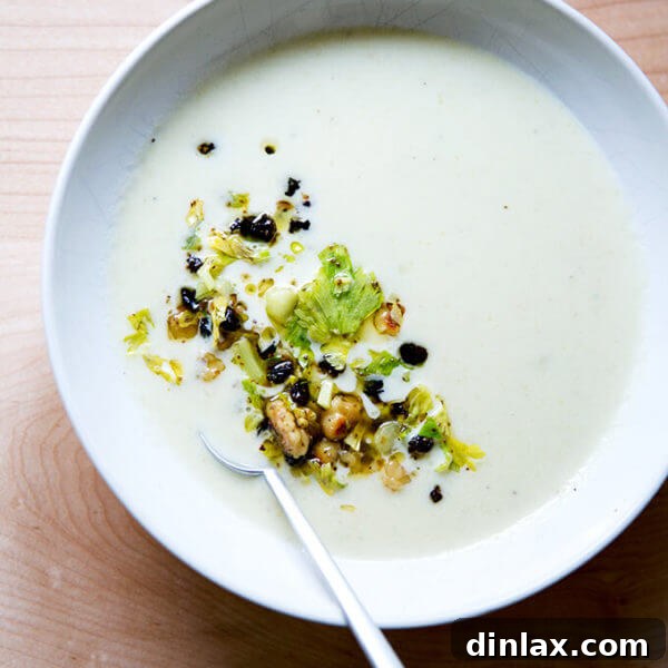 An overhead shot of a bowl of cream of celery soup with walnut salsa.