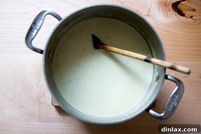 An overhead shot of a pot of cream of celery soup simmering on the stove, showing its smooth, creamy texture.