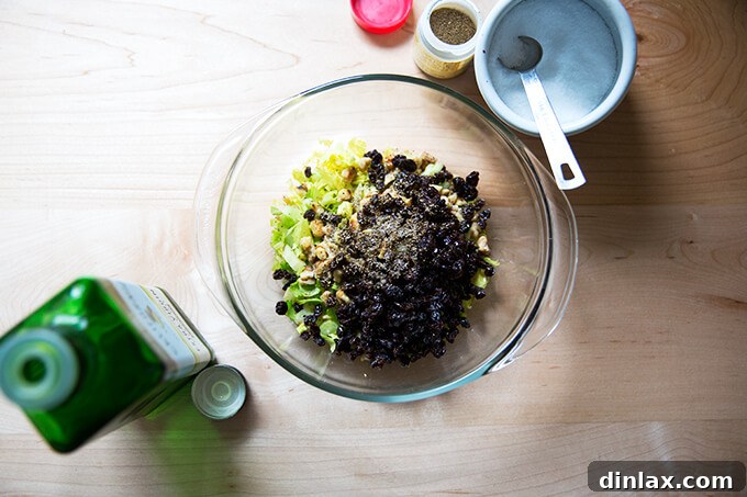 An overhead shot showcasing the fresh ingredients for the celery walnut salsa: toasted walnuts, chopped celery hearts and leaves, plumped currants, and celery seed, arranged beautifully.