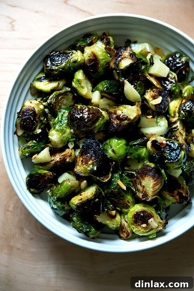 A serving bowl of roasted Brussels sprouts, almonds, and Manchego all tossed together, presented beautifully for guests.