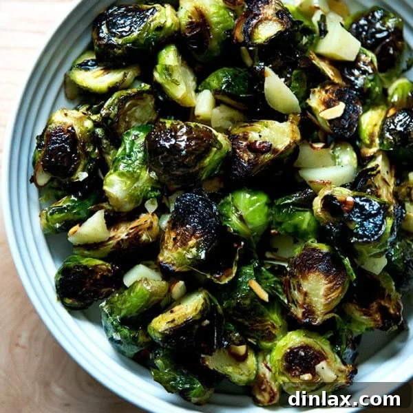 A bowl of roasted Brussels Sprouts with Almonds, Manchego, and balsamic, garnished and ready to serve.