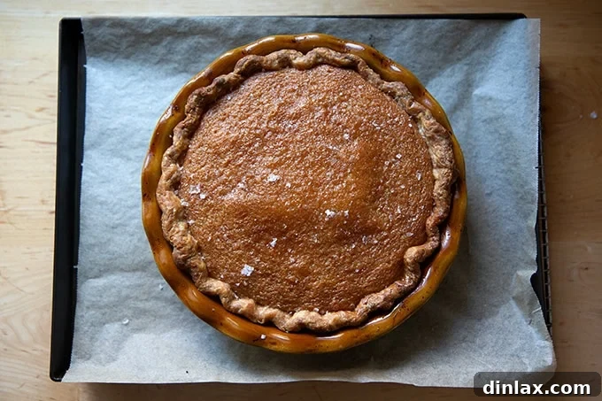 Sister Pie's Irresistible Salted Maple Pie 13 A freshly baked salted maple pie, golden and perfectly puffed at the edges, resting on a sheet pan, just out of the oven.