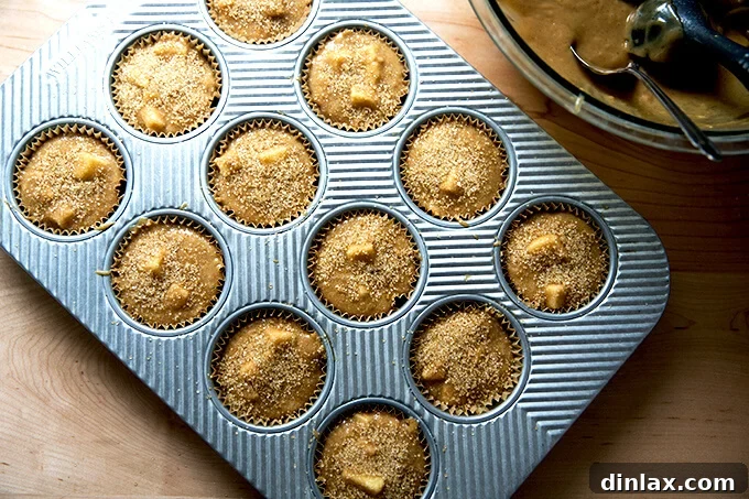 Harvest Apple Muffins 8 A muffin pan filled with batter, generously sprinkled with sparkling turbinado sugar, ready to be baked to perfection.