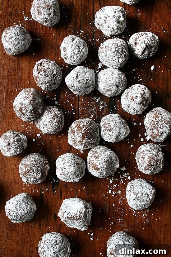 Rum balls are delicious. They are perfect for a crowd. They are perfect as a gift. They are perfect little bites of boozy goodness. I can’t think of a more perfect treat to have on hand this time of year. // alexandracooks.com A rustic wooden board laden with an abundance of rum balls, artfully arranged for a festive display.