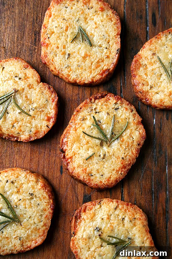Aunt Betsy's Signature Glogg 6 Unbaked Parmesan-Rosemary cracker slices with rosemary garnish on a baking sheet