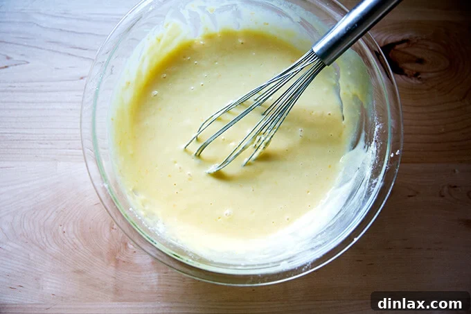 The smooth, pale yellow batter for the one-bowl orange ricotta loaf cake, perfectly whisked and ready for baking in a large mixing bowl.