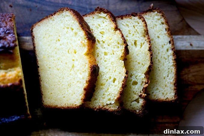 A perfectly sliced orange ricotta pound cake, revealing its incredibly moist and tender crumb, garnished with a light dusting of powdered sugar.