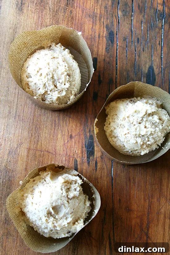 batter Decorative muffin liners, artfully arranged, brimming with coffeecake muffin batter and generously topped with streusel, poised for baking, showcasing the care in preparation.