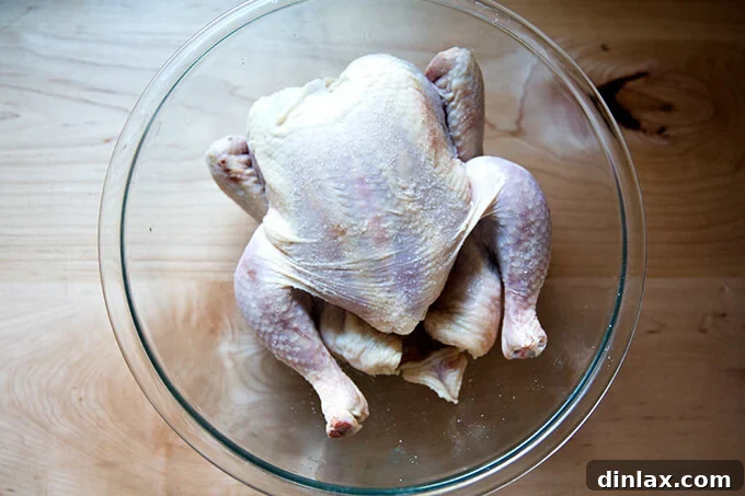 A whole salted chicken, resting in a bowl in the refrigerator.