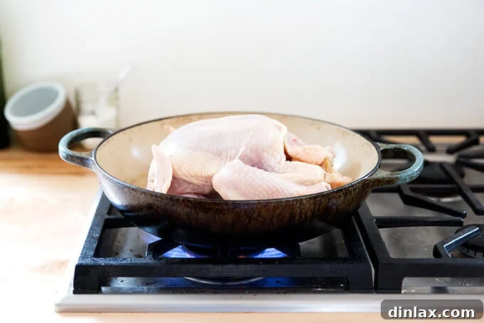 A whole raw chicken placed breast-side up in a preheated oven-safe skillet.