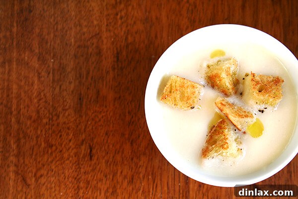 A close-up of creamy cauliflower and apple soup in a bowl, showing its velvety texture