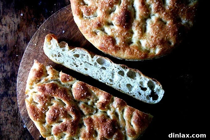 A rectangular sheet of golden Overnight, Refrigerator Focaccia topped with herbs and dimples, ready to be sliced.