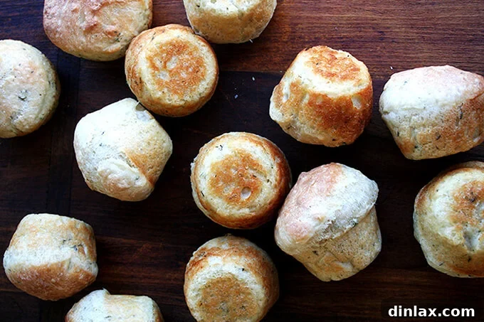 Golden-brown No-Knead Thyme Dinner Rolls baked in a round pan, dusted with fresh thyme leaves.