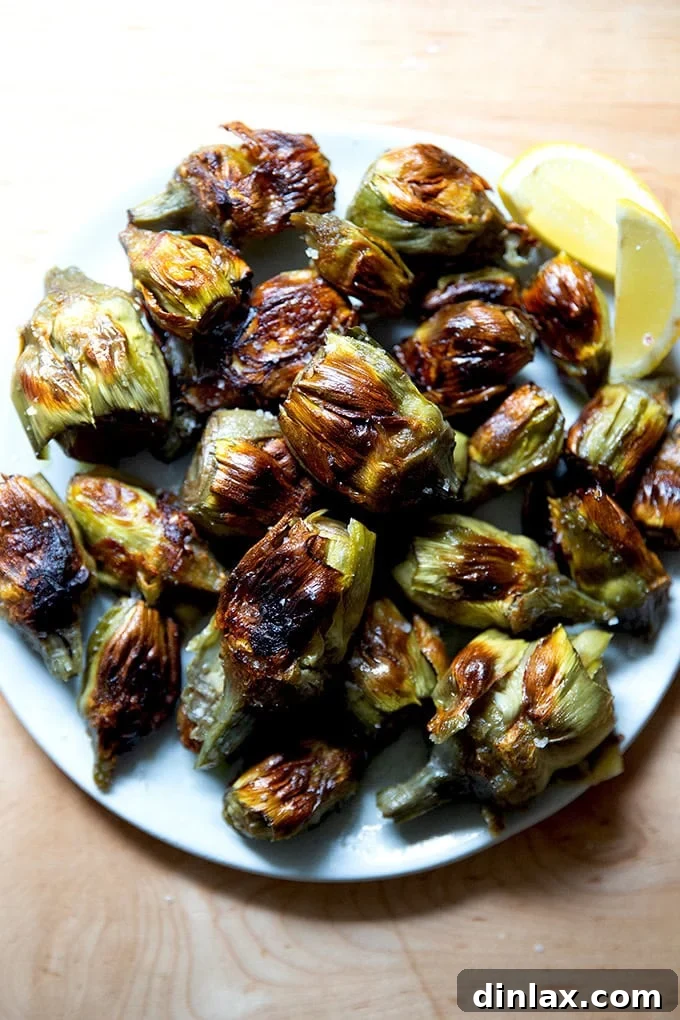 A plate of crispy baby artichokes served alongside a vibrant lemon half, inviting a final squeeze of fresh citrus.