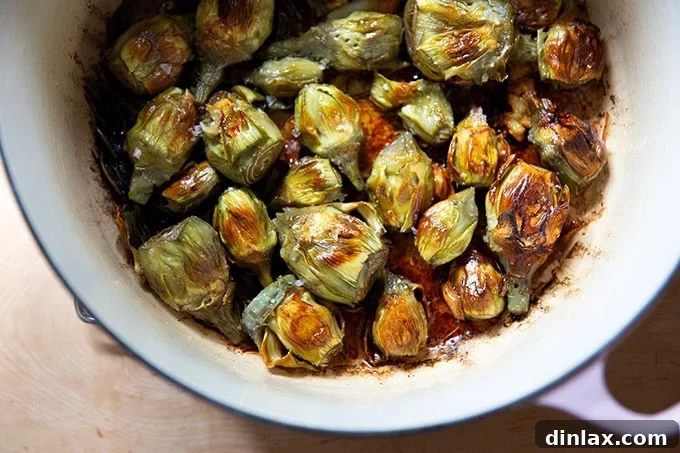 A large pot filled with just-cooked baby artichokes, evenly golden and crispy on both sides, signaling they are perfectly done.