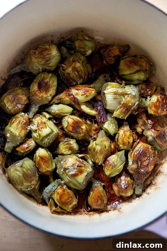 A close-up view of the perfectly golden-brown and crispy pan-roasted baby artichokes resting in the pot, ready to be served.
