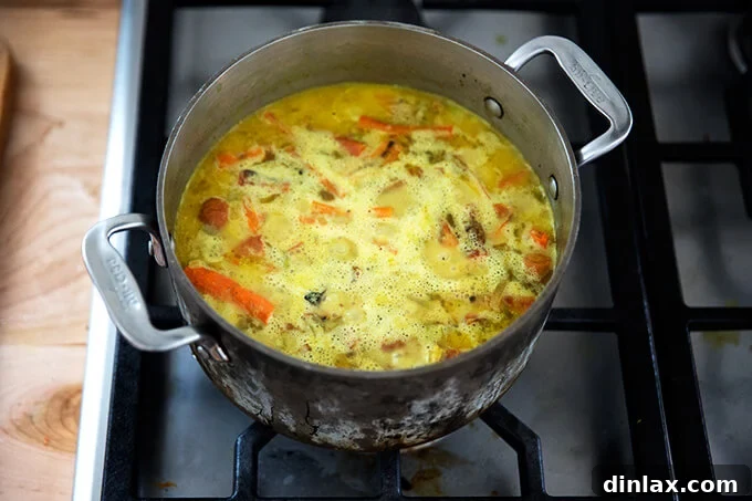 Curried Carrot Ginger Coconut Bliss 14 The vegan carrot-ginger soup mixture gently simmering, allowing flavors to meld and deepen.