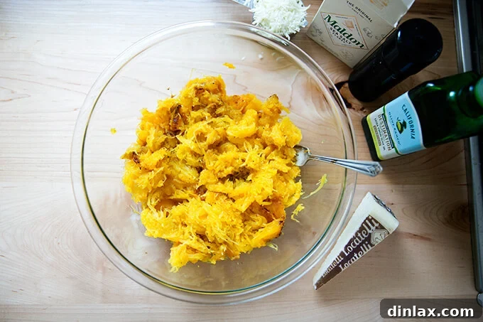 Spaghetti squash strands in a bowl, with olive oil and spices, ready for the Pecorino cheese.