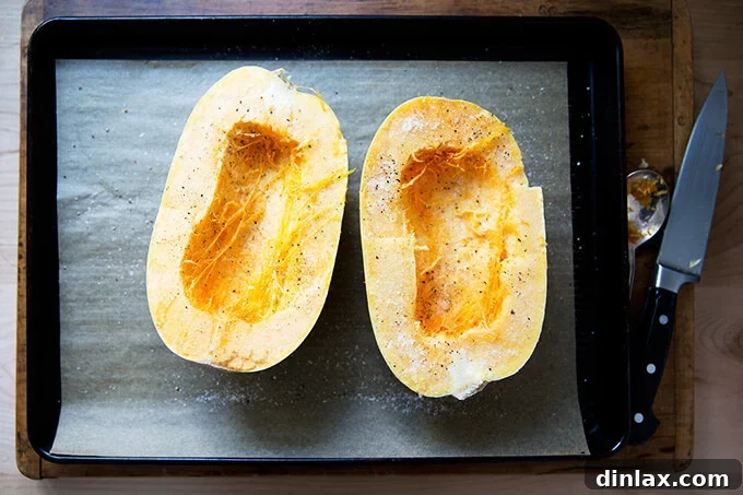 Seasoned spaghetti squash halves, sprinkled with salt and pepper, ready for roasting.
