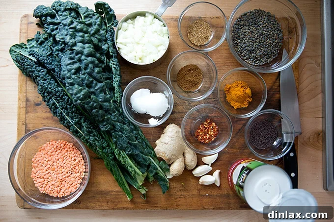 Creamy Coconut Kale Lentil Curry 3 A selection of fresh ingredients for curried lentils with kale and coconut milk, neatly arranged on a wooden board.