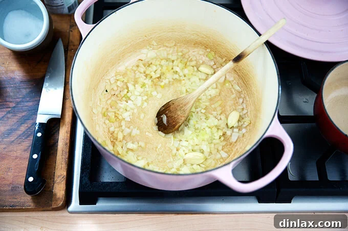 Creamy Coconut Kale Lentil Curry 6 Finely minced onions and smashed garlic cloves gently sautéing in coconut oil within a Dutch oven on the stovetop.