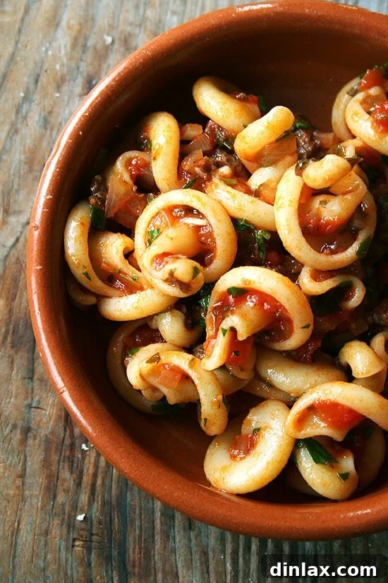 A beautifully plated dish of Gragnano Vesuvio pasta tossed with Marcella Hazan's white wine and parsley tomato sauce, topped with fresh herbs.