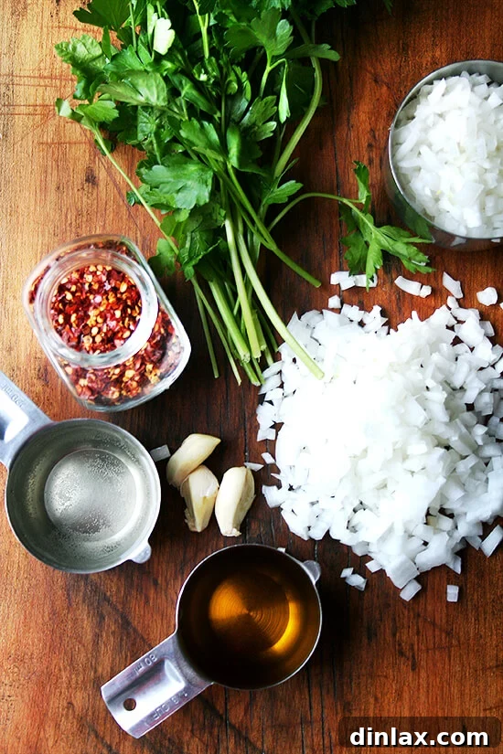 A selection of fresh ingredients, including onions, garlic, parsley, San Marzano tomatoes, and white wine, for the Hazan tomato sauce.