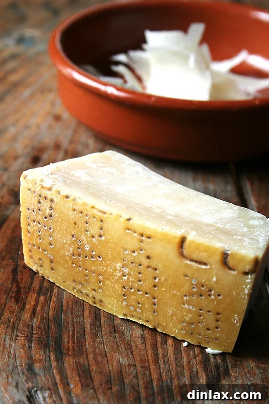A block of authentic Parmigiano Reggiano cheese, ready for grating to finish the pasta dish.