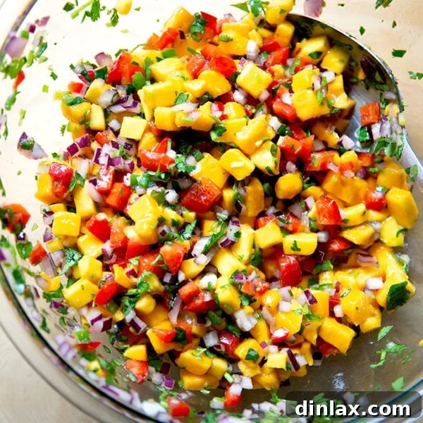 A vibrant bowl of sweet and spicy homemade mango salsa, accompanied by a stack of crispy tortilla chips, ready for dipping.