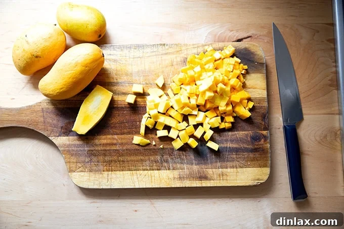 Finely diced ripe mango pieces perfectly cubed on a clean wooden cutting board, showcasing their vibrant golden color and readiness for the salsa mixture.