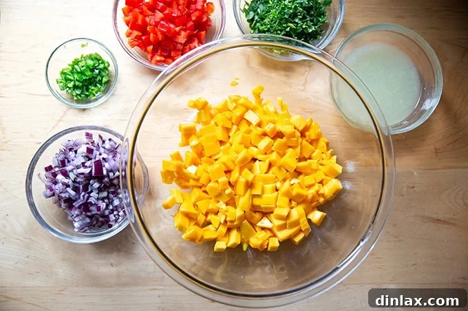 All diced mango salsa ingredients – mango, red bell pepper, red onion, and jalapeño – along with freshly squeezed lime juice, meticulously presented on a countertop before mixing.