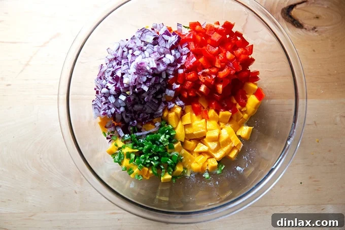 Diced mango, red onion, and red bell pepper combined in a large mixing bowl, forming the base of the homemade salsa.
