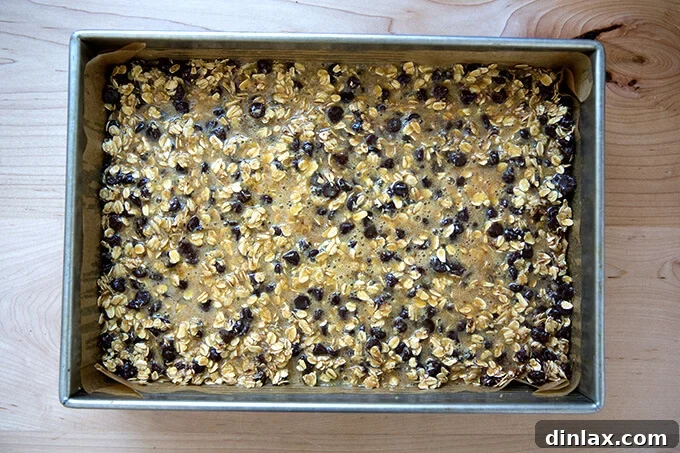 Gooey oat bar topping poured over baked crust, ready for the oven