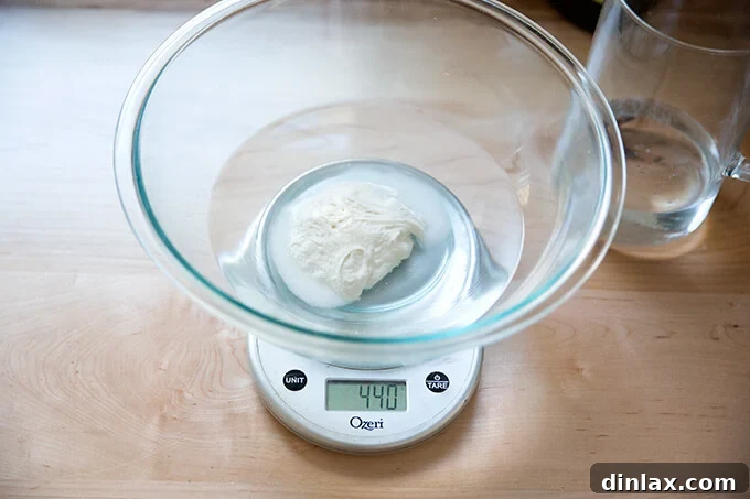 The Easiest Sourdough Focaccia: Perfect for Beginners 10 Measuring and adding 440g of water to the sourdough starter and salt mixture