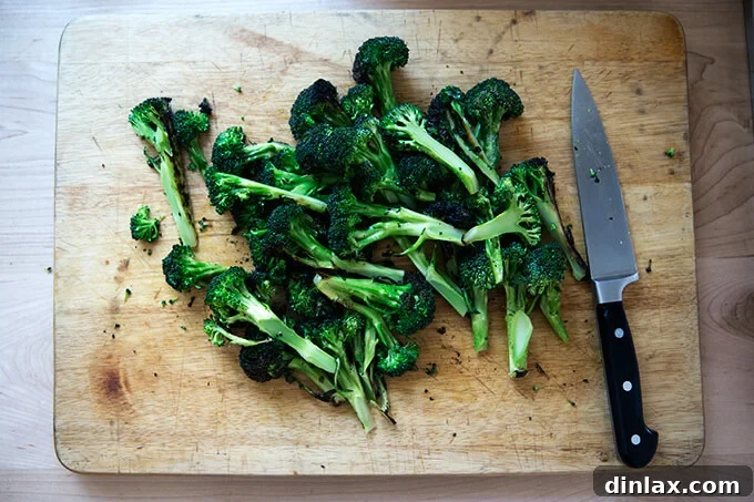 Sliced charred broccoli on a cutting board, prepared for the salad.