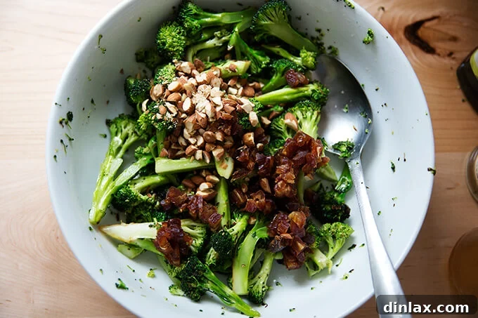 Charred broccoli being tossed with dressing, then dates and almonds are added.