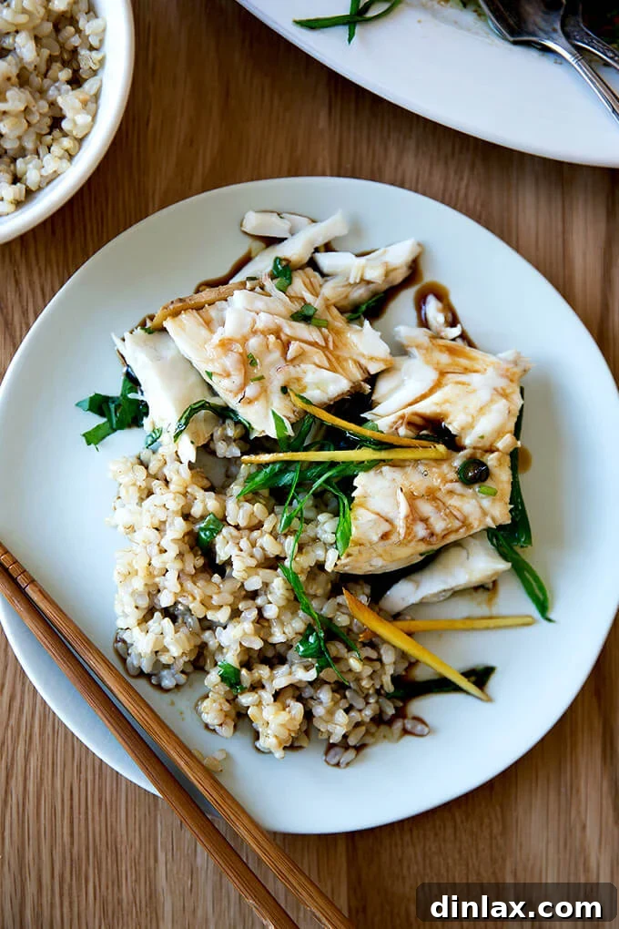 Ginger-Scallion Infused Steamed Whole Fish 19 A plate of Chinese-style steamed Branzino served alongside wholesome brown rice, a perfect pairing.