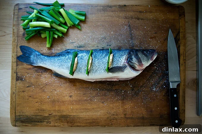 Ginger-Scallion Infused Steamed Whole Fish 8 Branzino being prepped for steaming with slits stuffed with ginger and scallions.