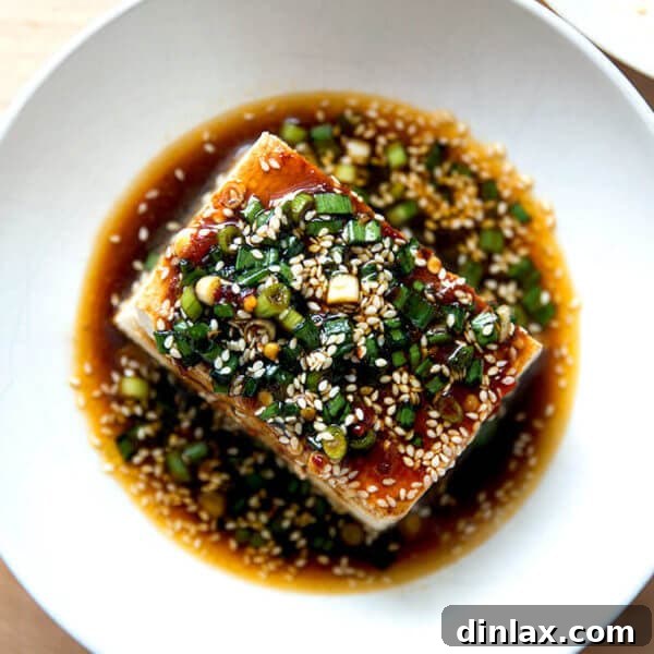 A bowl of warm tofu topped with sesame scallion sauce.