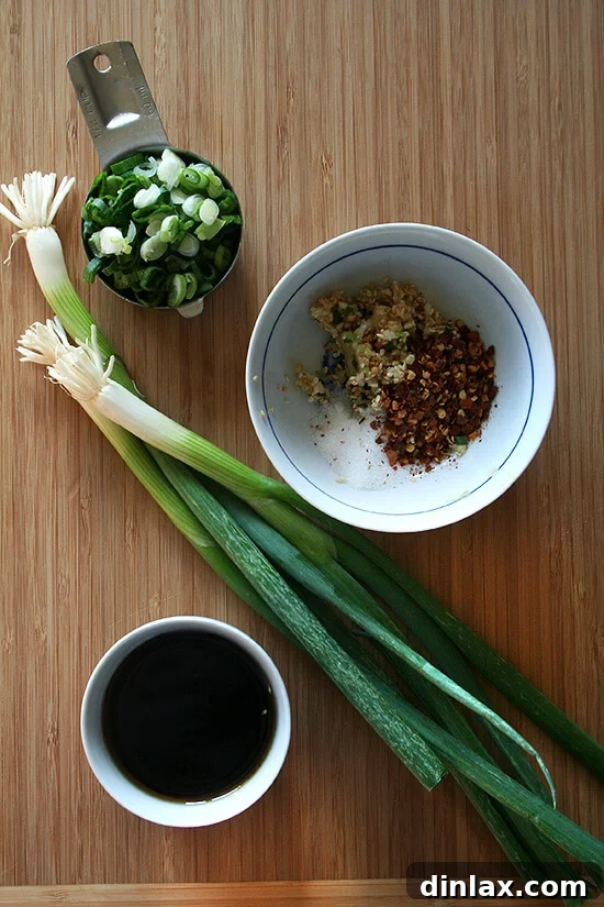 Velvety Tofu with a Garlic Kick 3 A board displaying fresh scallions, spices, and soy sauce bottles, ready for sauce preparation.