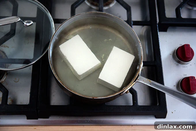 Velvety Tofu with a Garlic Kick 6 A halved block of tofu simmering in water, showcasing the easy preparation.