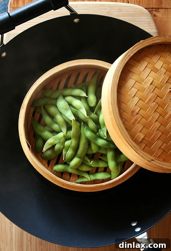 Velvety Tofu with a Garlic Kick 10 Fresh edamame pods steaming gently in a bamboo steamer basket set within a wok.